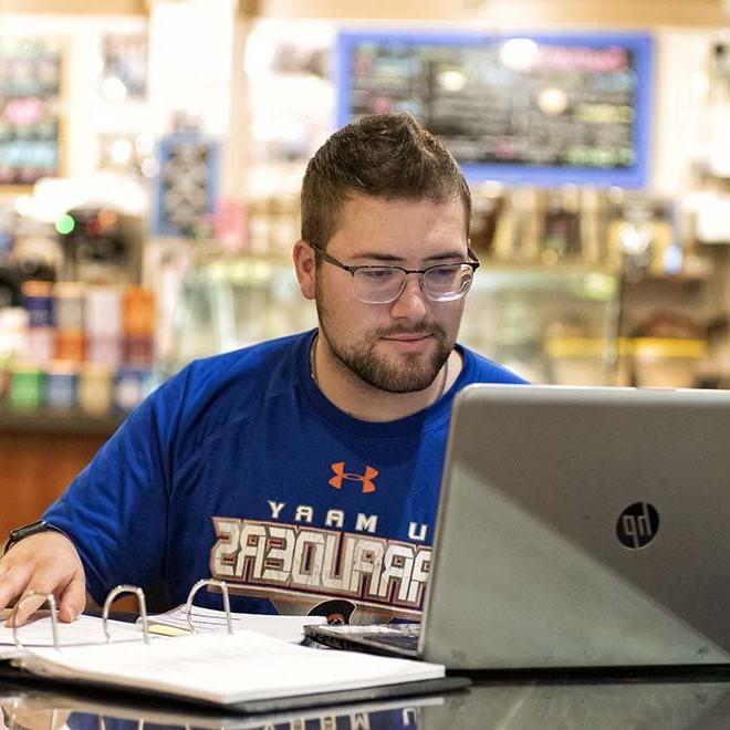 男成人学生在咖啡店用手提电脑学习