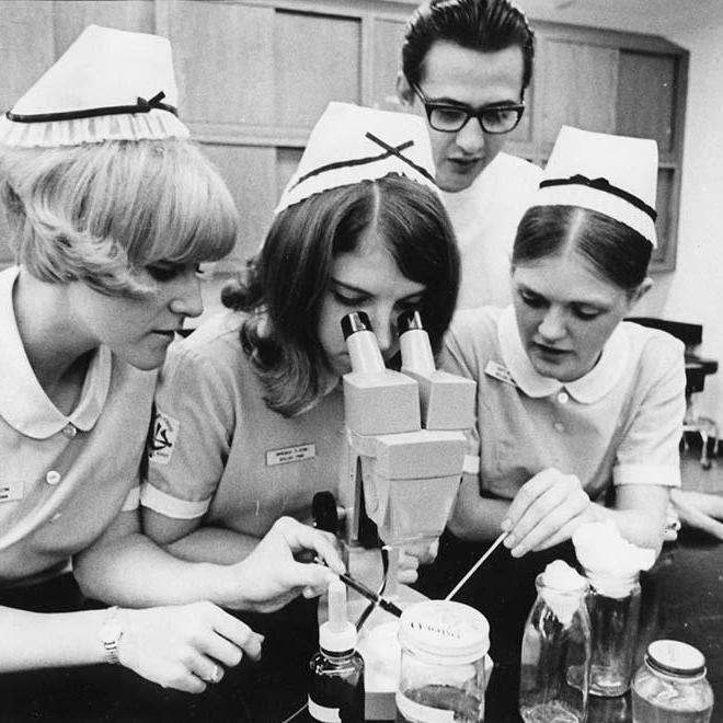 1960年，一名护生在显微镜下和她周围的其他三名护生.