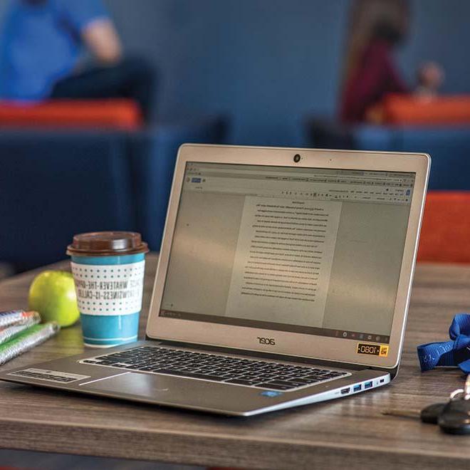 Laptop on table with coffee, apple, and notebooks